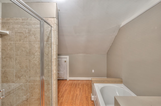 bathroom with vaulted ceiling, independent shower and bath, and wood-type flooring