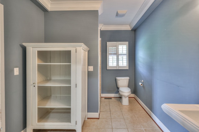 bathroom with toilet, ornamental molding, and tile patterned floors