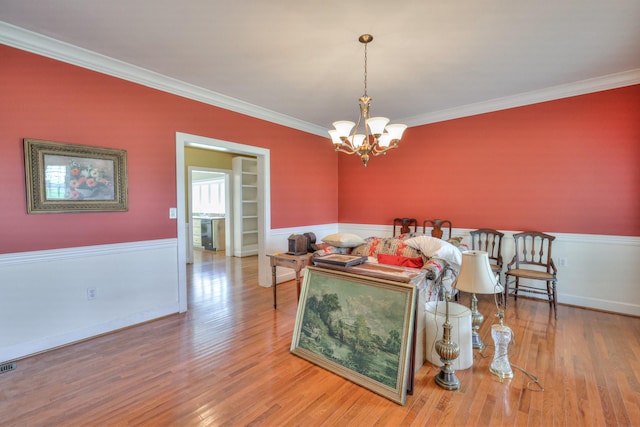 living room with built in shelves, crown molding, an inviting chandelier, and wood-type flooring