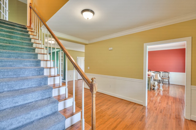 stairs featuring hardwood / wood-style floors and ornamental molding