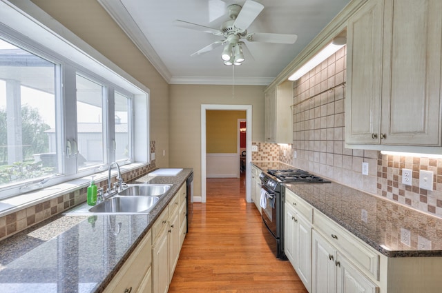 kitchen with sink, black gas range, decorative backsplash, light hardwood / wood-style floors, and crown molding