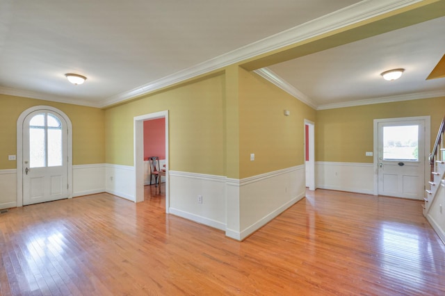 foyer featuring light wood-type flooring, ornamental molding, and a healthy amount of sunlight