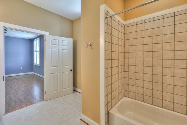 bathroom featuring tiled shower / bath combo and tile patterned flooring