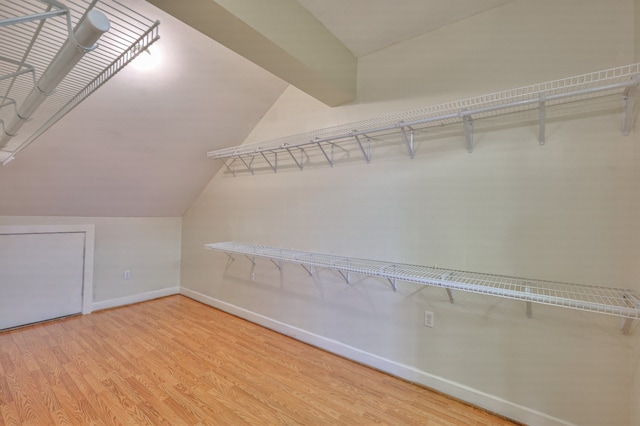 walk in closet featuring light hardwood / wood-style flooring and lofted ceiling