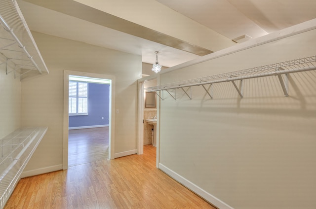 walk in closet featuring light hardwood / wood-style floors and a notable chandelier