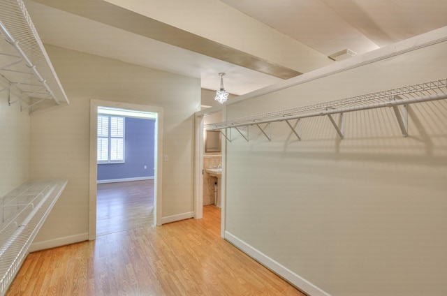 spacious closet featuring light wood-type flooring and a chandelier
