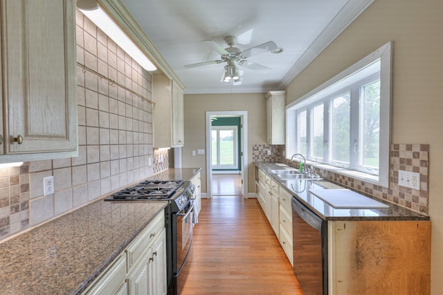 kitchen featuring backsplash, sink, light wood-type flooring, dishwasher, and gas range oven