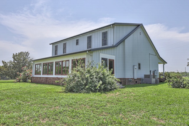 back of property with a yard and central AC