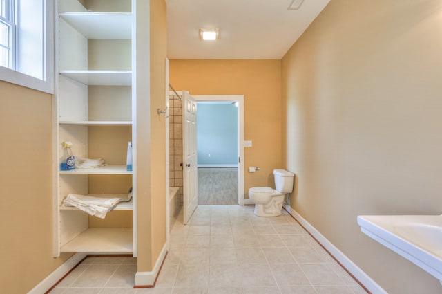 bathroom featuring toilet, shower / washtub combination, and tile patterned floors