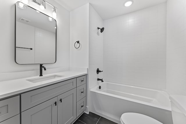 full bathroom with tile patterned floors, tiled shower / bath, toilet, and vanity