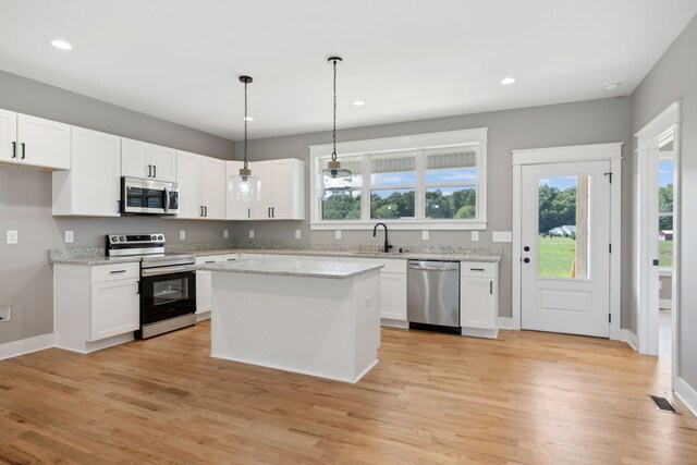 kitchen featuring a kitchen island, white cabinets, light hardwood / wood-style flooring, and appliances with stainless steel finishes