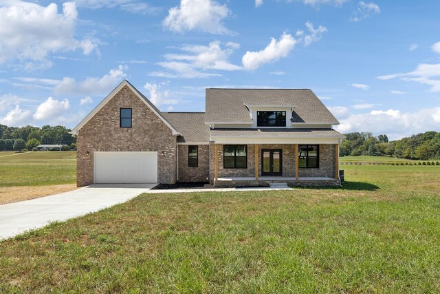 view of front of property featuring covered porch, a front yard, and a garage