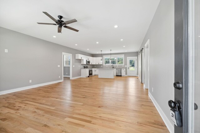 unfurnished living room featuring light wood-style floors, baseboards, a ceiling fan, and recessed lighting