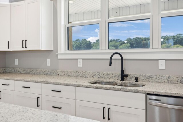 kitchen with white cabinets, dishwasher, light stone counters, and a wealth of natural light