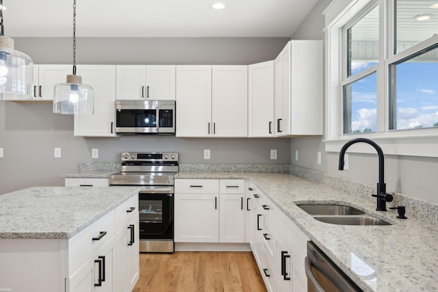 kitchen featuring appliances with stainless steel finishes, light wood-style floors, white cabinetry, and a sink