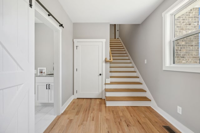 staircase with a barn door and wood-type flooring