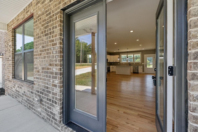 view of exterior entry with brick siding and a sink