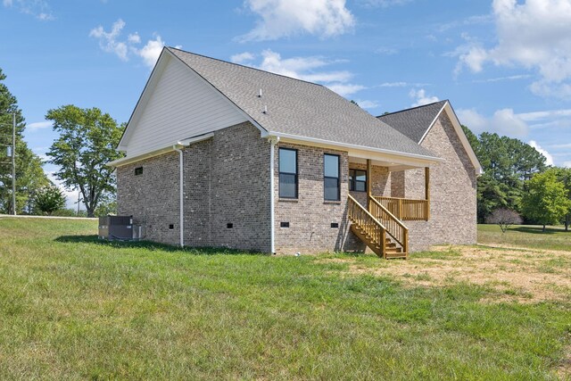 rear view of house with central AC and a yard