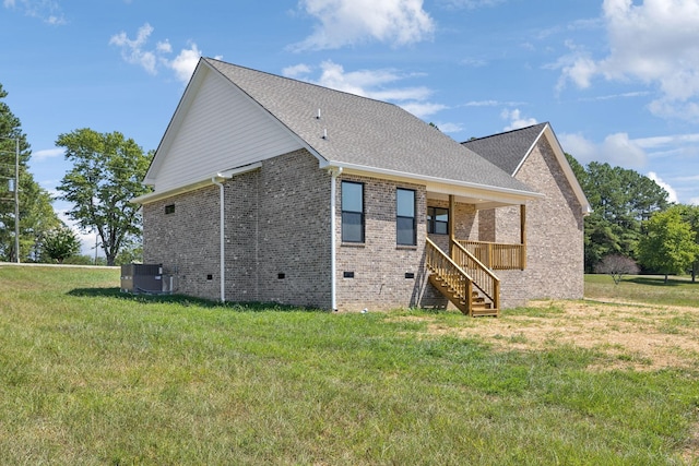 rear view of house with a shingled roof, central AC unit, crawl space, a yard, and brick siding