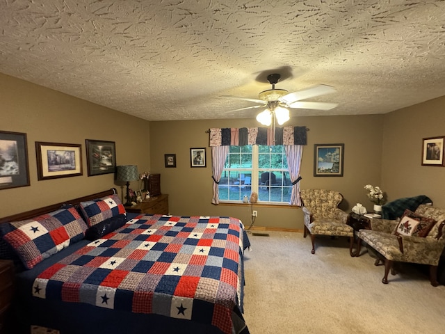 bedroom with ceiling fan, carpet, and a textured ceiling