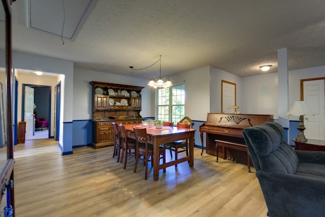 dining area featuring light hardwood / wood-style floors, a notable chandelier, and a textured ceiling