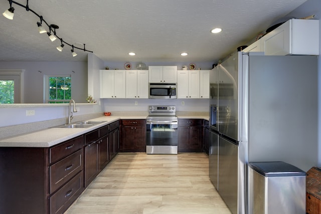 kitchen with track lighting, white cabinetry, light hardwood / wood-style flooring, sink, and appliances with stainless steel finishes