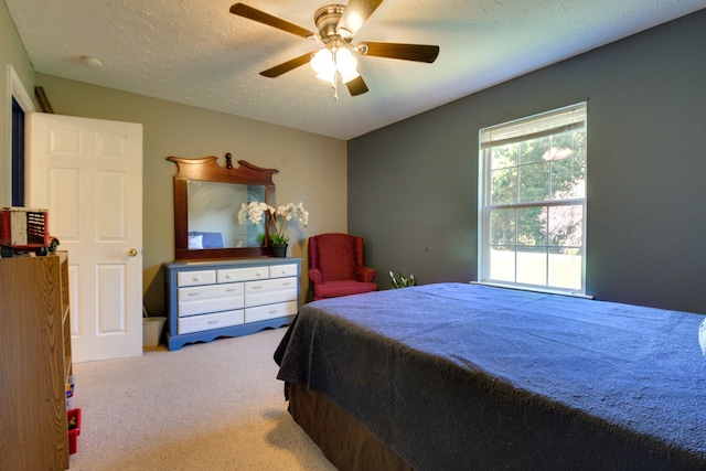 bedroom with ceiling fan, carpet, and a textured ceiling