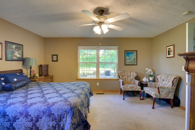 carpeted bedroom featuring ceiling fan and a textured ceiling