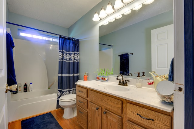 full bathroom with hardwood / wood-style flooring, shower / bath combo, toilet, vanity, and a textured ceiling