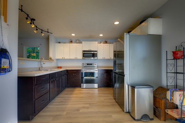 kitchen featuring track lighting, dark brown cabinets, stainless steel appliances, white cabinets, and light hardwood / wood-style floors