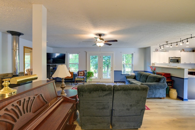 living room featuring light wood-type flooring, track lighting, a textured ceiling, and ceiling fan