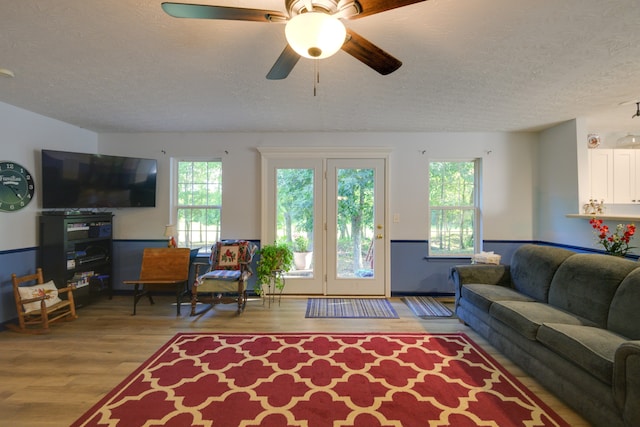 living room with ceiling fan, light hardwood / wood-style floors, and a textured ceiling