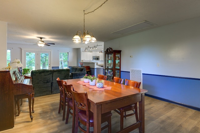 dining room featuring light wood-type flooring and ceiling fan with notable chandelier