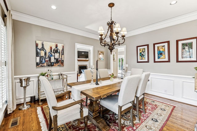 dining room with wood-type flooring, an inviting chandelier, and crown molding