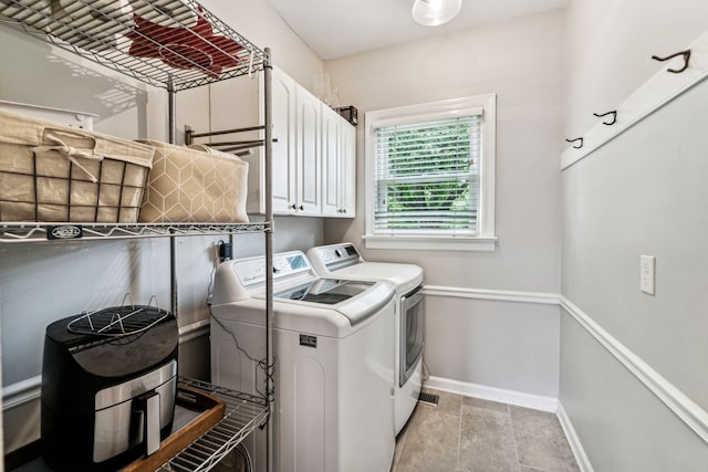 washroom with cabinets, washer and clothes dryer, and light tile patterned floors