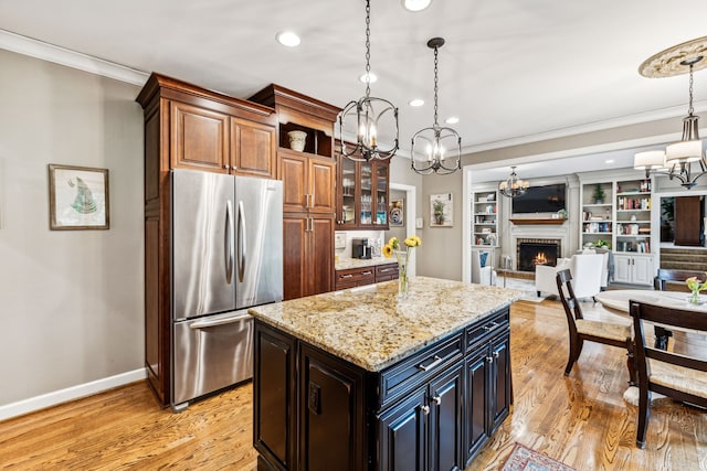 kitchen with hanging light fixtures, an inviting chandelier, stainless steel fridge, and a kitchen island