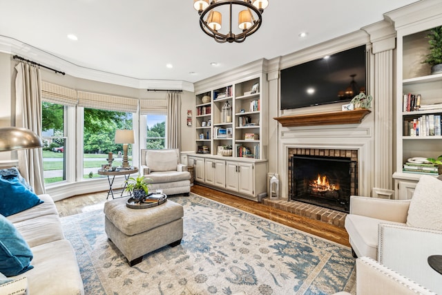 living room featuring built in features, hardwood / wood-style floors, a fireplace, and an inviting chandelier