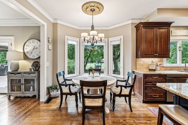 dining room with ornamental molding, a healthy amount of sunlight, a notable chandelier, and hardwood / wood-style flooring