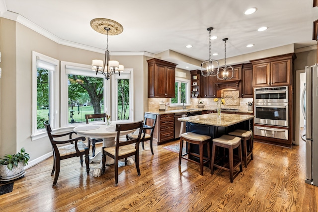 kitchen featuring a center island, light stone countertops, appliances with stainless steel finishes, dark hardwood / wood-style flooring, and a notable chandelier