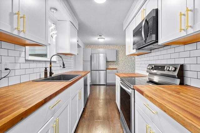 kitchen with sink, decorative backsplash, appliances with stainless steel finishes, and butcher block countertops