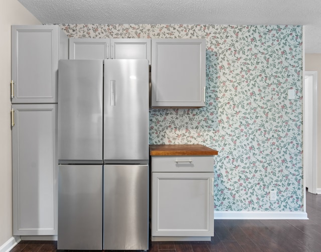 kitchen featuring a textured ceiling, stainless steel fridge, wood counters, and dark hardwood / wood-style floors