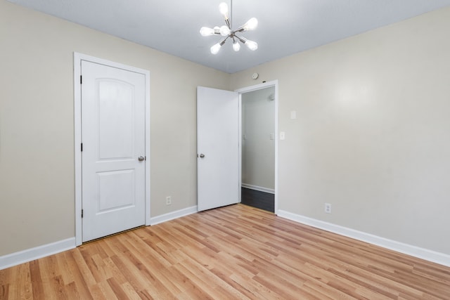 unfurnished bedroom with light hardwood / wood-style floors, a closet, and a chandelier