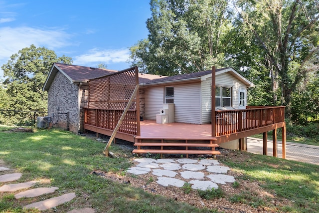 rear view of house with central AC unit, a wooden deck, and a lawn