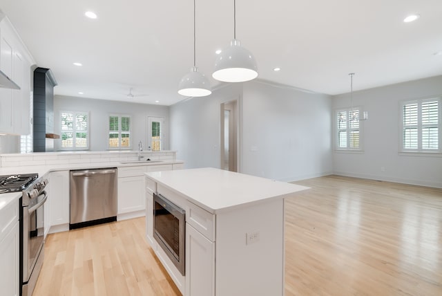 kitchen featuring pendant lighting, stainless steel appliances, white cabinetry, and a wealth of natural light