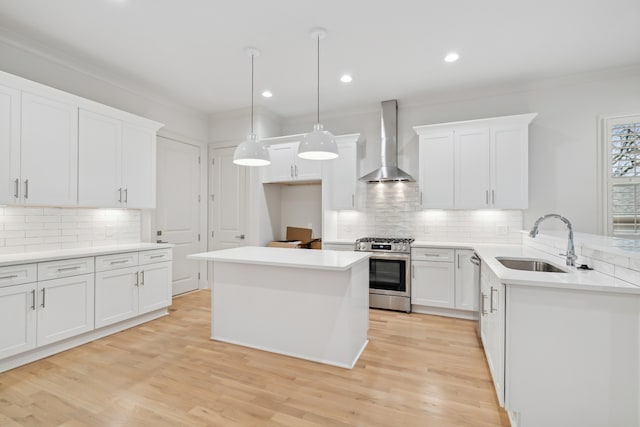 kitchen featuring appliances with stainless steel finishes, wall chimney exhaust hood, sink, light hardwood / wood-style flooring, and white cabinetry