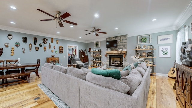 living room with light hardwood / wood-style floors, crown molding, ceiling fan, and a fireplace