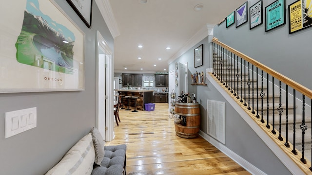 entrance foyer featuring crown molding and light hardwood / wood-style floors