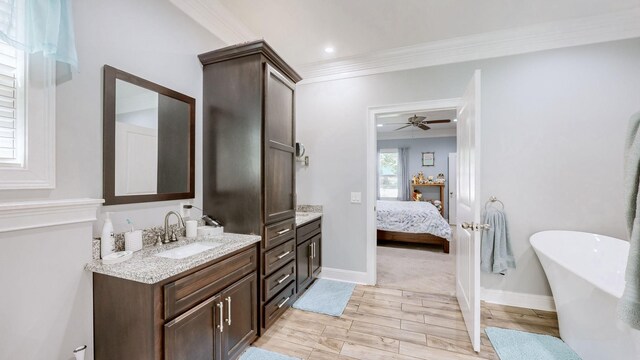 bathroom with ceiling fan, a bathtub, ornamental molding, and vanity