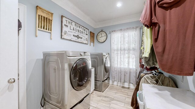 washroom featuring washing machine and clothes dryer, light wood-type flooring, crown molding, and a healthy amount of sunlight