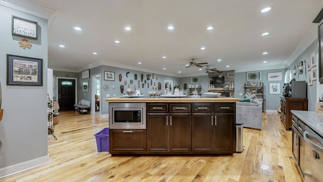 kitchen featuring appliances with stainless steel finishes, dark brown cabinetry, light hardwood / wood-style flooring, ceiling fan, and crown molding